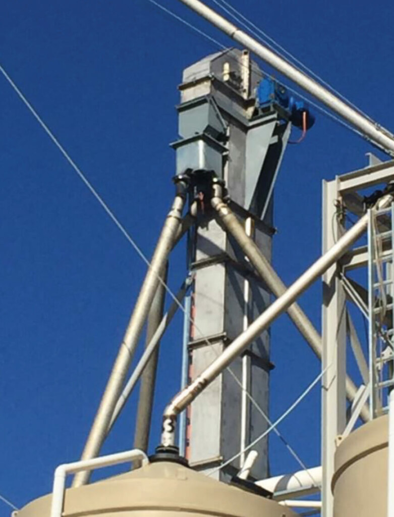 The top of a grain silo with a crane and belt conveyors attached to it.